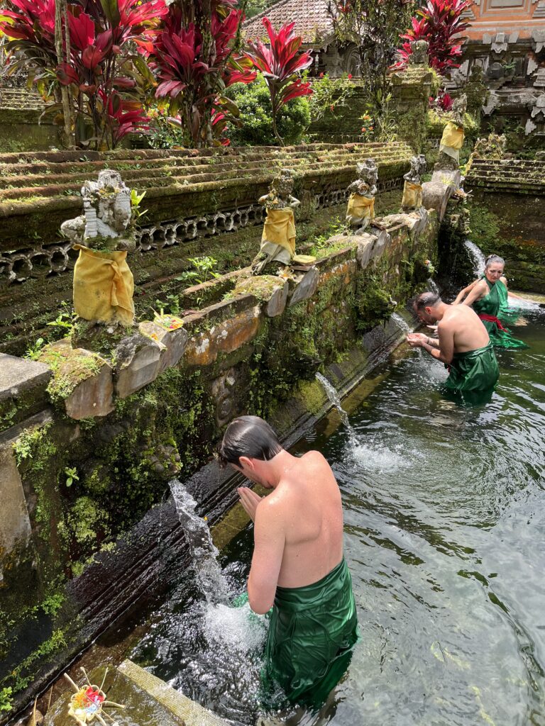 Visitors performing melukat purification ritual at a quiet water temple in Sebatu, Bali